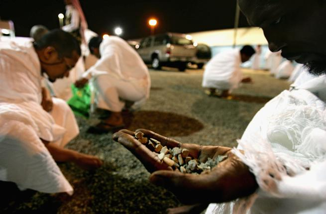 Pilgrims resting at Muzdalifah under the night sky, with pebbles collected nearby